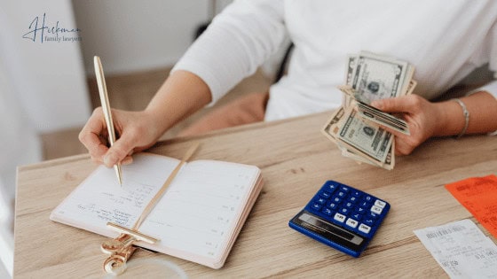 What Is Financial Abuse - Hickman Family Lawyers - woman holding money and writing in notebook